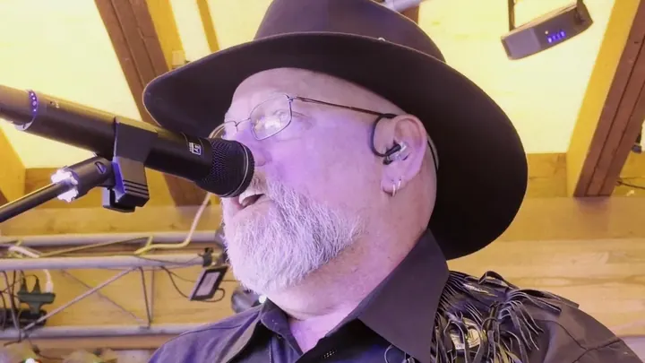 Singer in a black hat at the mic